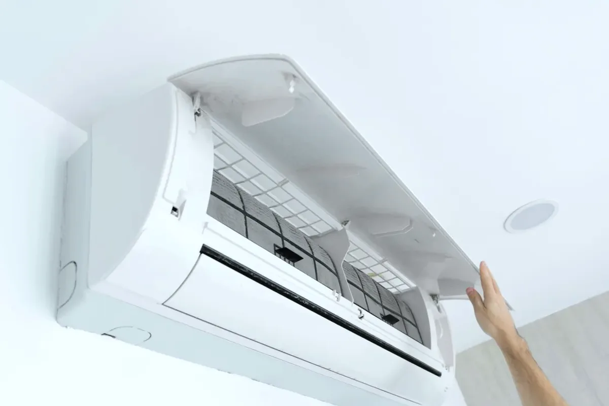 Hand opening the cover of a wall-mounted ductless air conditioner